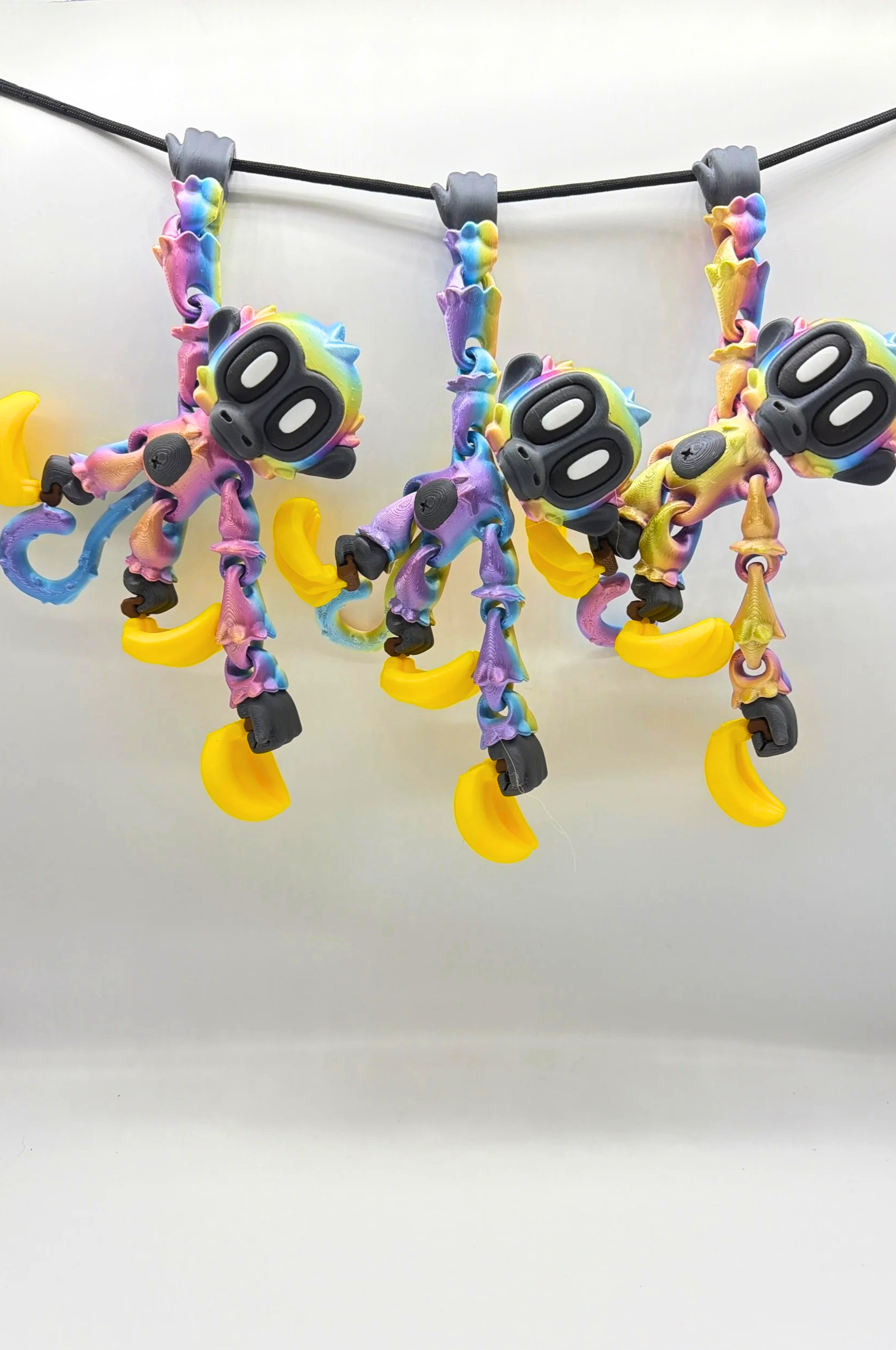 Rainbow monkey figures with bananas hanging on a wire