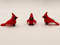 Three red cardinal figurines on a white surface